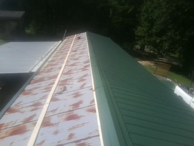 Old rusted panels beside newly installed green metal roofing — Wind Damage Roof Repair by Roofing Brothers in Mitchell