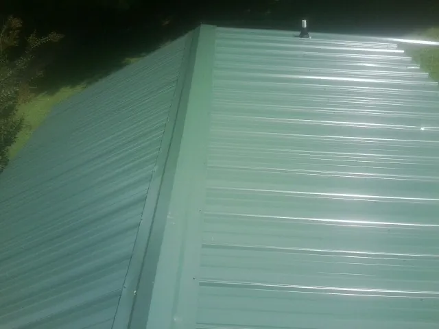 New green metal panels meeting at the ridge of a roof — Flat Roof Repair work by our crew in Mitchell